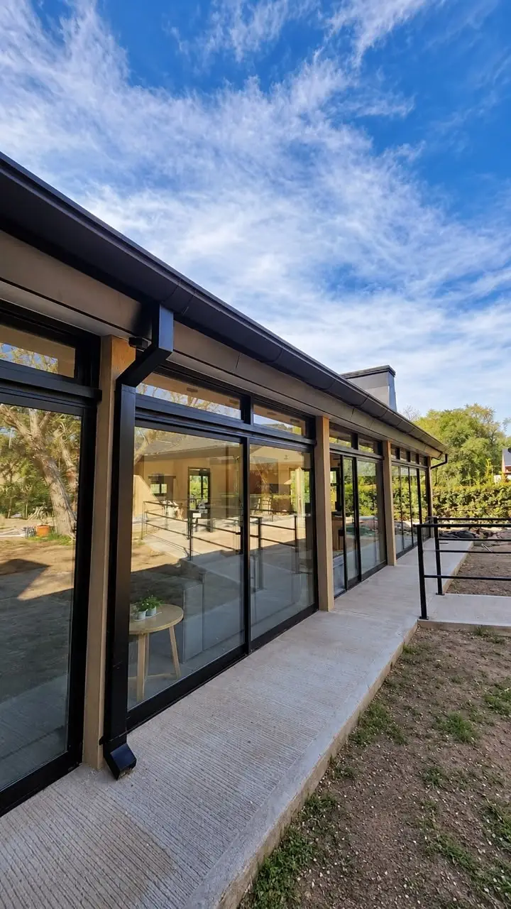 Galería con ventanales de piso a techo que dan al jardín de Haus Leben